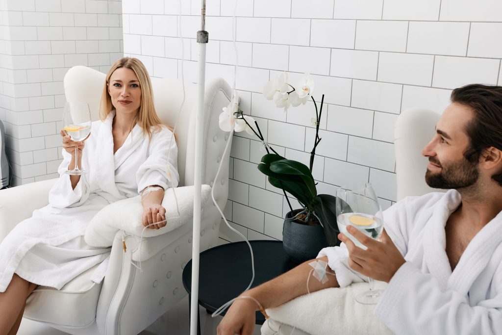 A man and a woman in white robes relax in plush recliners while receiving an IV infusion, showcasing the calming and restorative experience of IV Therapy at Revive & Drip in Washington, PA. This image captures the essence of rejuvenation and wellness provided by the clinic's comprehensive range of services. Along with IV Therapy, Revive & Drip offers Botox, fillers, aesthetic treatments, and personalized weight loss programs, all designed to enhance health and beauty in a luxurious, serene environment. The image highlights the comfort and effectiveness of the treatments, inviting clients to experience the revitalization that Revive & Drip provides.