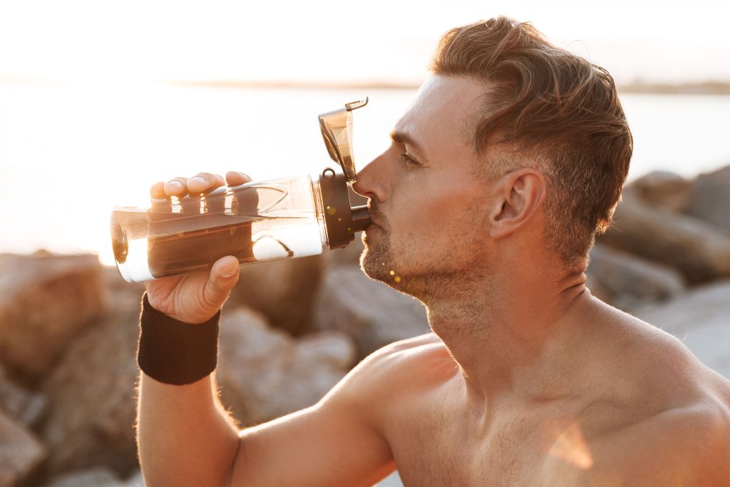 Shirtless man taking a break and drinking from a water bottle, symbolizing the rejuvenation and energy restoration offered by Performance IV Therapy at Revive and Drip Medical Spa. This image captures the essence of enhanced athletic performance and recovery, as the therapy is designed to replenish essential nutrients, boost energy levels, and aid in muscle recovery. Revive and Drip provides a comprehensive range of services, including Botox, fillers, aesthetic treatments, IV therapy, and weight loss solutions, all tailored to help clients achieve peak performance, both physically and aesthetically. The man’s posture, relaxed yet invigorated, reflects the balanced approach of Performance IV Therapy, which not only enhances physical stamina but also promotes overall wellness. The refreshing water bottle further emphasizes the hydration and nutrient replenishment aspects of the treatment, ensuring that clients leave feeling revitalized and ready to take on their next challenge with renewed vigor and strength.