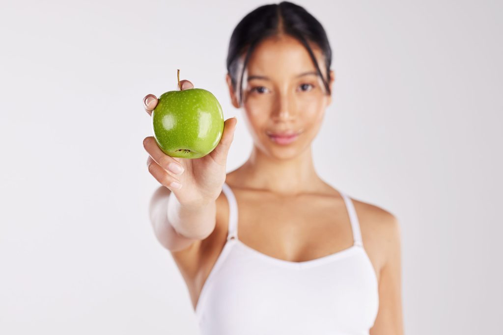 A woman in a white tank top smiling as she holds a green apple, symbolizing health and the idea of 'keeping the doctor away,' which aligns with the Virus Defense focus of The Defender IV Therapy offered at Revive and Drip Medical Spa. This image represents the spa's commitment to enhancing the body's natural defenses against illness through advanced IV therapy treatments that boost the immune system. The green apple, a symbol of health and vitality, complements the holistic wellness approach at Revive and Drip, where clients can also access a wide range of aesthetic and health-focused services, including Botox injections, dermal fillers, and personalized aesthetic treatments. Additionally, the spa provides specialized IV therapy options designed to replenish vital nutrients and support overall well-being, along with tailored weight loss programs that help clients achieve their fitness and health goals. The woman's relaxed and confident demeanor in the image reflects the spa's nurturing environment, where each treatment is designed to promote not only physical wellness but also a sense of rejuvenation and self-care. The combination of aesthetic treatments, wellness therapies, and IV infusions at Revive and Drip underscores the spa's dedication to providing comprehensive care that addresses both immediate beauty needs and long-term health goals, making it a trusted destination for those seeking to enhance their appearance and protect their health in a luxurious and supportive setting.