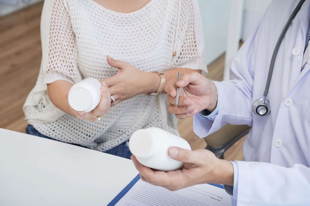 A doctor carefully explaining the usage of hormone replacement therapy pills to a woman, holding a prescription bottle in her hands. The scene reflects the personalized care and attention provided at Revive and Drip in Washington, PA, where patients receive comprehensive guidance on their HRT treatments. This image emphasizes the importance of understanding and properly administering hormone therapy, ensuring that clients can safely and effectively manage their symptoms. Revive and Drip offers a range of services, including HRT, Botox, dermal fillers, IV therapy, and weight loss programs, all aimed at enhancing health and well-being under professional supervision.