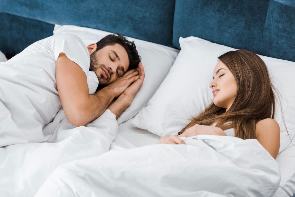 A young, attractive couple peacefully sleeping in a white bed, highlighting the rejuvenating benefits of Hormone Replacement Therapy (HRT) at Revive and Drip in Washington, PA. This image represents the deep rest and balance that can be achieved through HRT, which helps restore hormonal levels to support energy, mood, and overall well-being. At Revive and Drip, our expert team offers personalized HRT plans to address symptoms of hormonal imbalance, helping clients reclaim their vitality and improve their quality of life. Alongside HRT, Revive and Drip provides a full range of services including Botox, dermal fillers, IV therapy, and weight loss treatments, all designed to enhance health and beauty for both men and women.