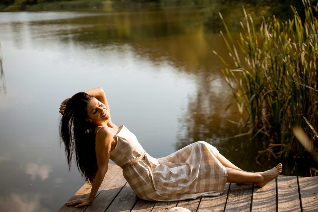 a woman sitting on a dock by water